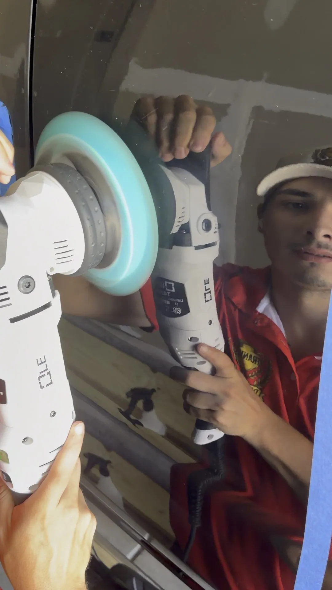A machine polisher on a black panel during paint correction