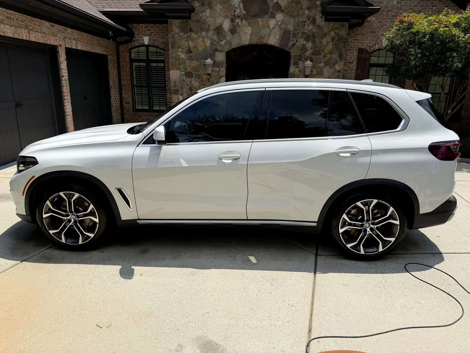 A finished white SUV on a residential driveway after a full detail